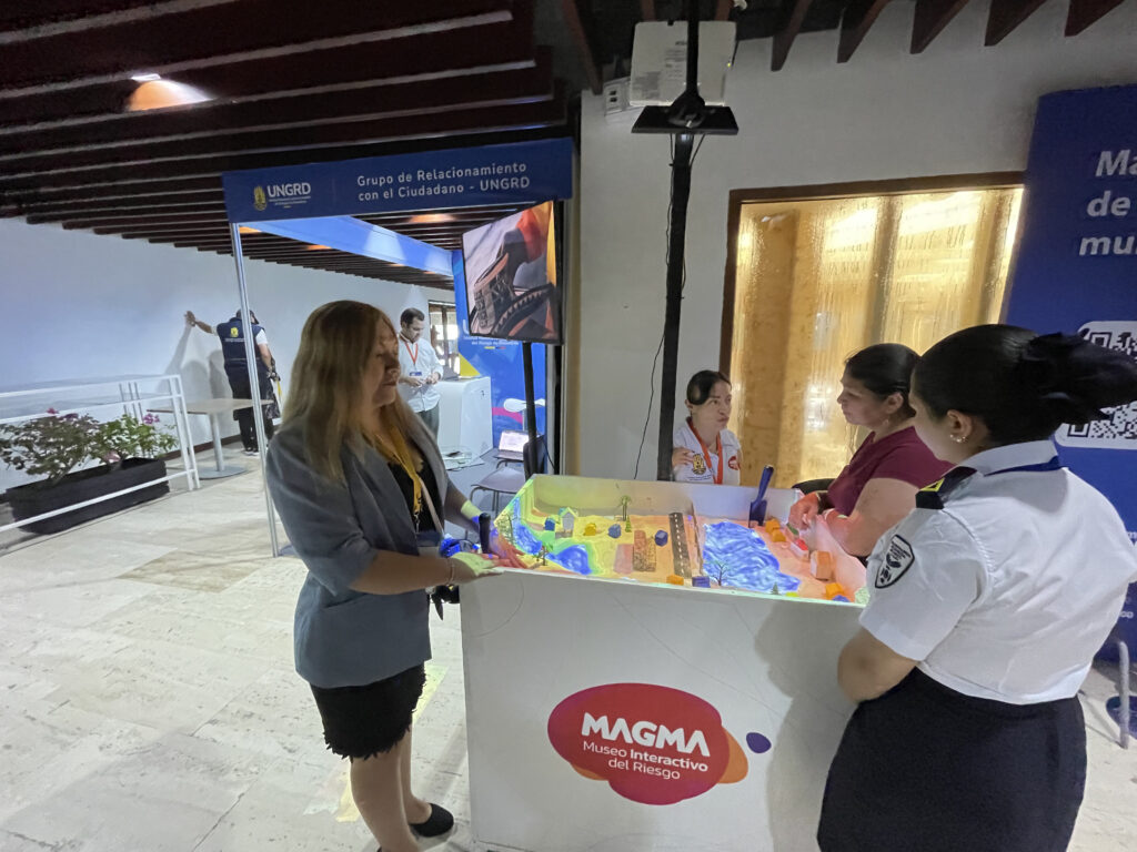 Aparece Rosa Maria Juarez en un stand donde se observa una maqueta que refleja un riesgo de desastre para la población.